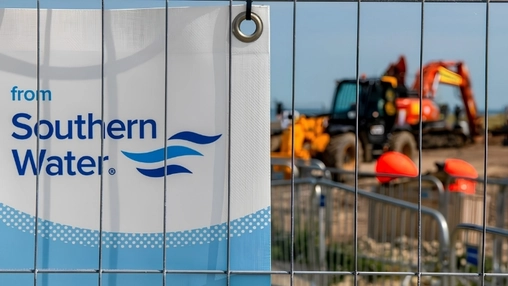 Southern Water branded banner on a metal fence with a yellow construction excavator in the background