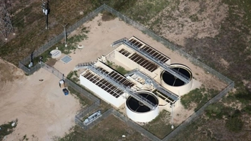 Aerial view of a water treatment facility with circular clarifier tanks and rectangular treatment beds